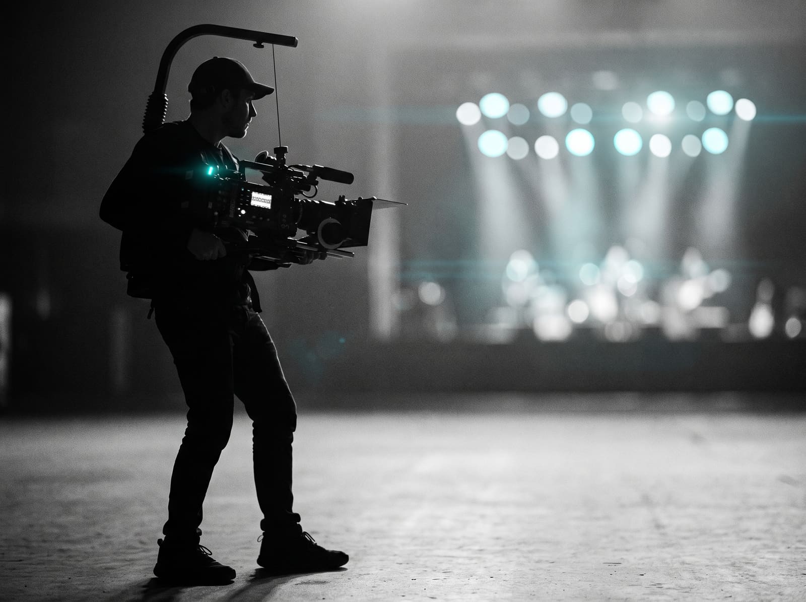 A camera operator silhouetted against stage lights at a live event.